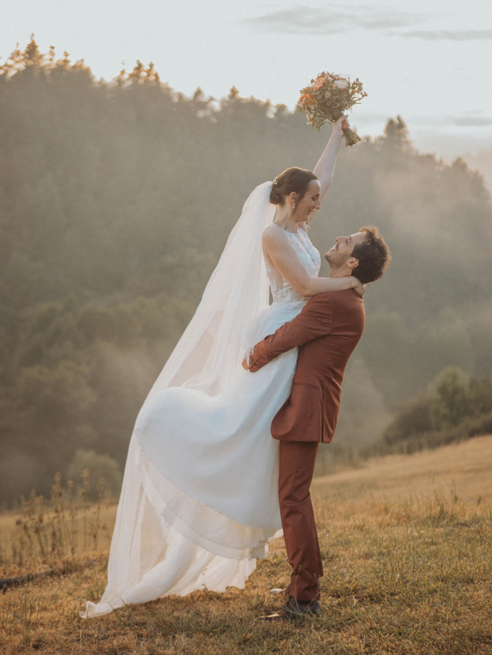 Le marié porte sa femme pour la séance photo du mariage près du Puy-en-Velay